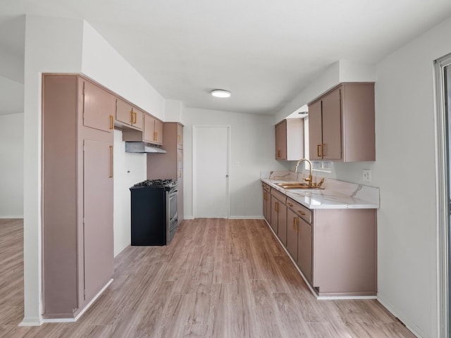 kitchen featuring light wood finished floors, stainless steel range with gas cooktop, baseboards, light countertops, and a sink