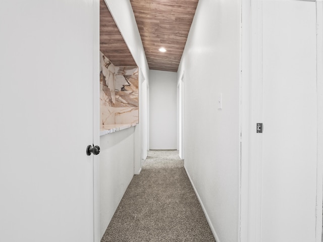 corridor featuring wood ceiling, baseboards, and carpet