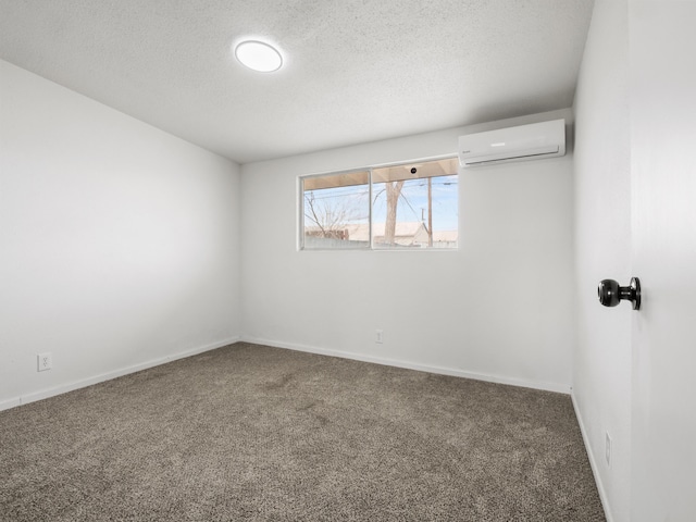 spare room featuring carpet flooring, baseboards, a wall mounted air conditioner, and a textured ceiling