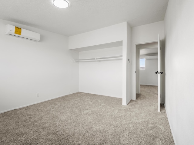 unfurnished bedroom featuring an AC wall unit and carpet floors