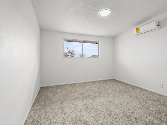 carpeted spare room with baseboards, a textured ceiling, and a wall unit AC