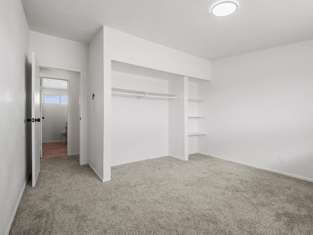 unfurnished bedroom featuring a closet, a textured ceiling, baseboards, and carpet floors