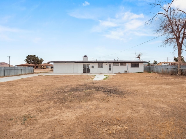 back of house featuring a chimney and fence