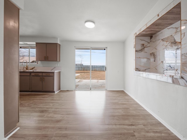 unfurnished dining area with light wood-style flooring, baseboards, and a sink