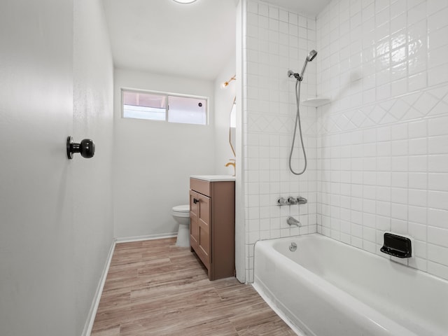 bathroom featuring vanity, wood finished floors, baseboards, tub / shower combination, and toilet