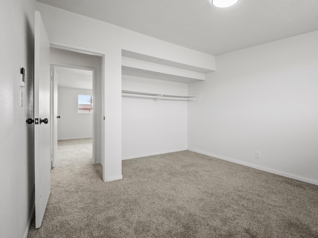 unfurnished bedroom featuring carpet, baseboards, and a textured ceiling