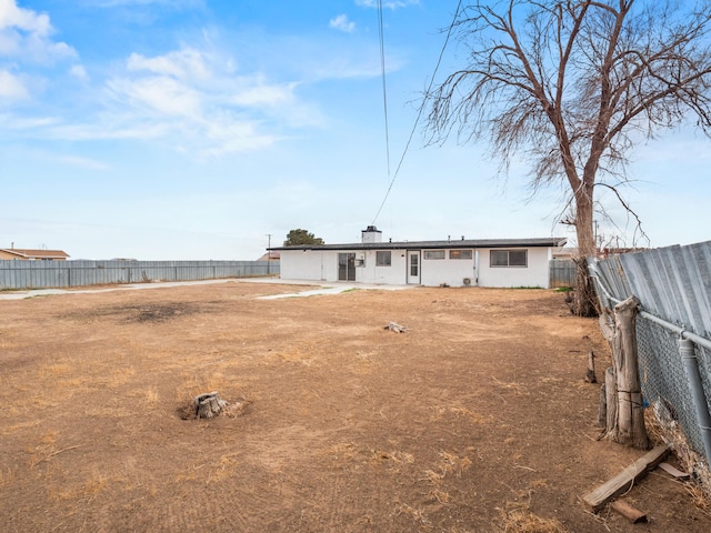 back of house featuring a fenced backyard and a chimney