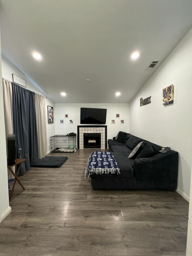 living room with a tile fireplace, dark hardwood / wood-style floors, and vaulted ceiling