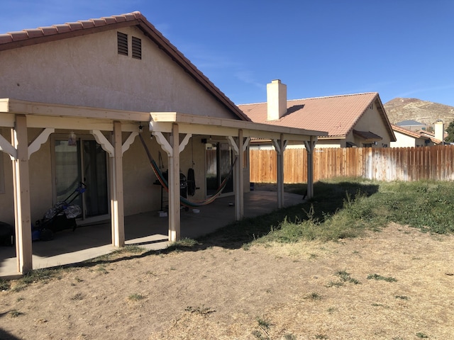 back of property with a mountain view and a patio