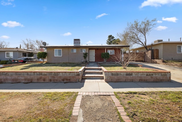 single story home with stucco siding, driveway, fence, and a gate