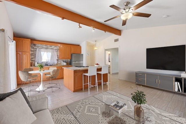 kitchen with visible vents, open floor plan, a center island, freestanding refrigerator, and vaulted ceiling with beams