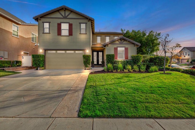 view of front of property featuring french doors, a garage, and a lawn