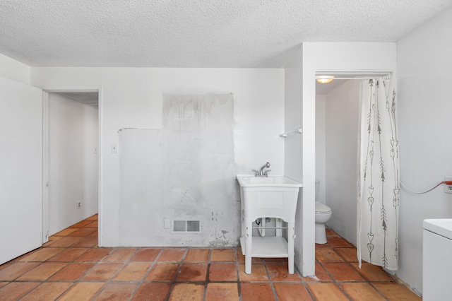 bathroom featuring toilet, visible vents, and a textured ceiling