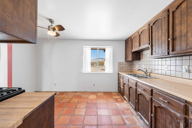 kitchen with dark brown cabinetry, a sink, a ceiling fan, light countertops, and decorative backsplash