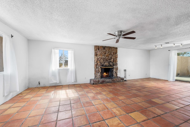 unfurnished living room featuring light tile patterned floors, a stone fireplace, and a wealth of natural light