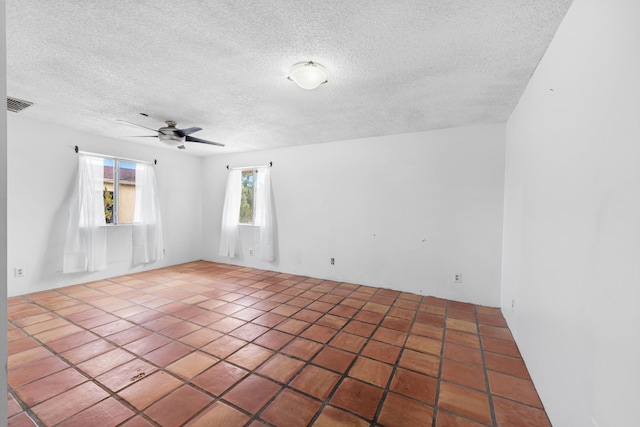 spare room featuring a textured ceiling, visible vents, and a ceiling fan