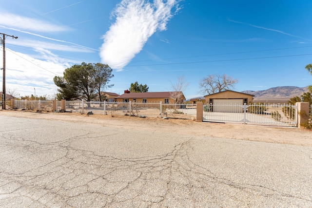 view of front of home featuring a fenced front yard, a mountain view, driveway, and an attached garage