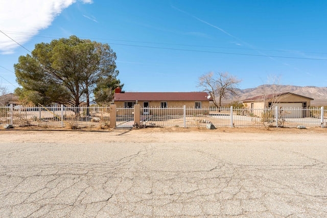 view of front facade with a fenced front yard, a mountain view, and stucco siding