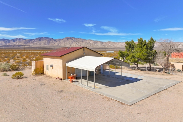 exterior space featuring a carport, fence, a mountain view, and concrete driveway