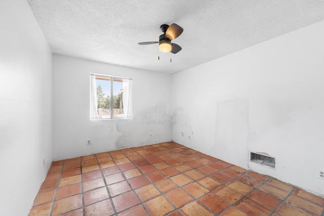 spare room with ceiling fan, visible vents, and a textured ceiling