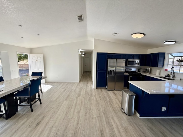 kitchen with stainless steel appliances, lofted ceiling, blue cabinets, and a sink