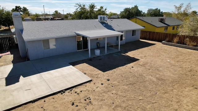 back of property featuring roof with shingles, stucco siding, central AC unit, a patio area, and a fenced backyard