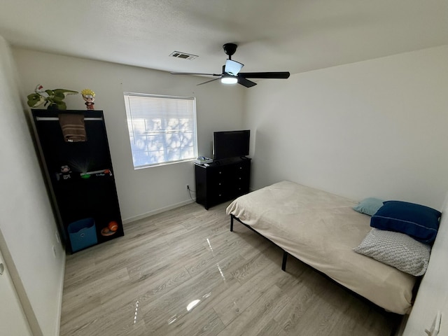 bedroom featuring ceiling fan, light wood-type flooring, visible vents, and baseboards