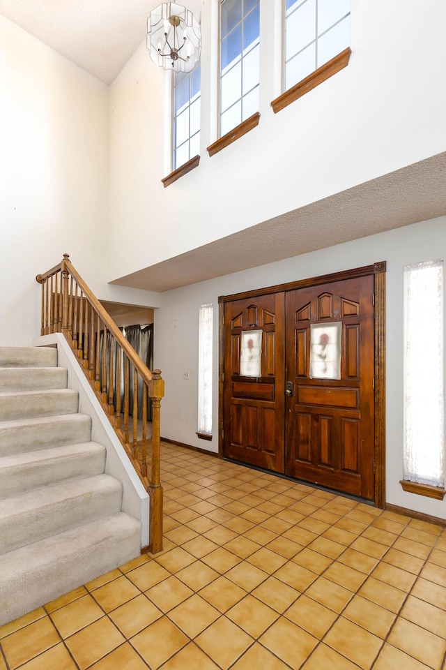 tiled foyer entrance featuring a notable chandelier and a towering ceiling