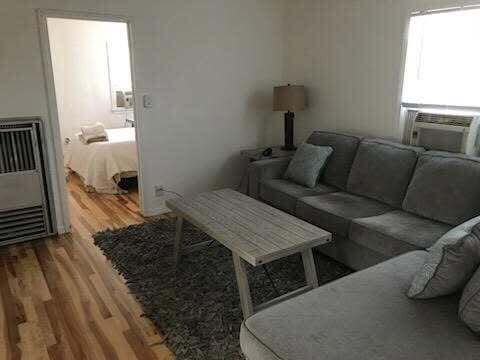 living room featuring heating unit, cooling unit, and wood finished floors