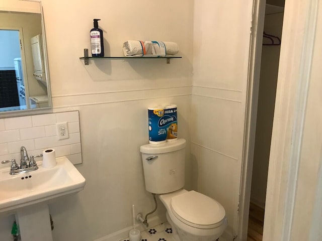 half bathroom with tasteful backsplash, a sink, and toilet