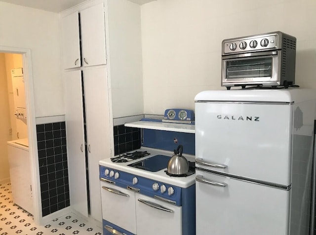 kitchen with white appliances, white cabinetry, tile walls, light countertops, and blue cabinetry