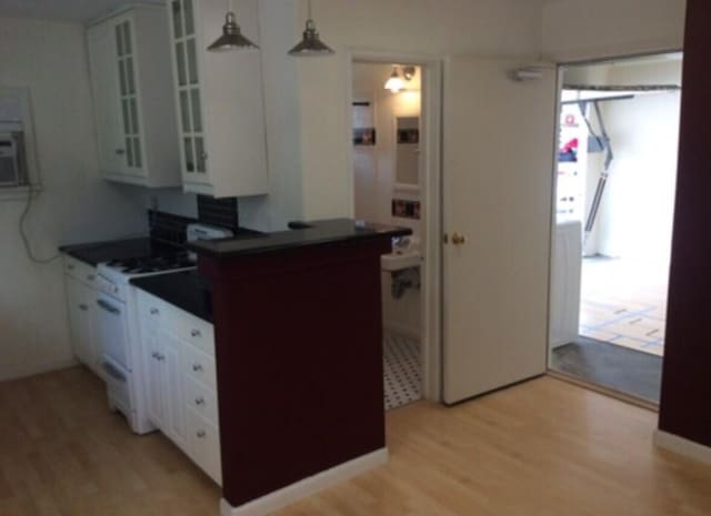 kitchen featuring dark countertops, light wood-style flooring, white cabinetry, and white gas stove