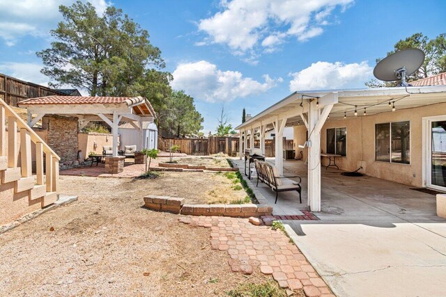 view of yard with an outdoor structure, a patio, a fenced backyard, a shed, and a gazebo