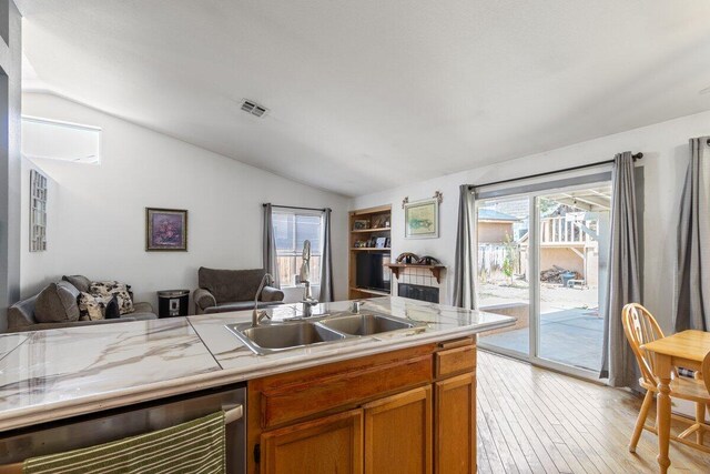 kitchen featuring a sink, light countertops, open floor plan, lofted ceiling, and visible vents