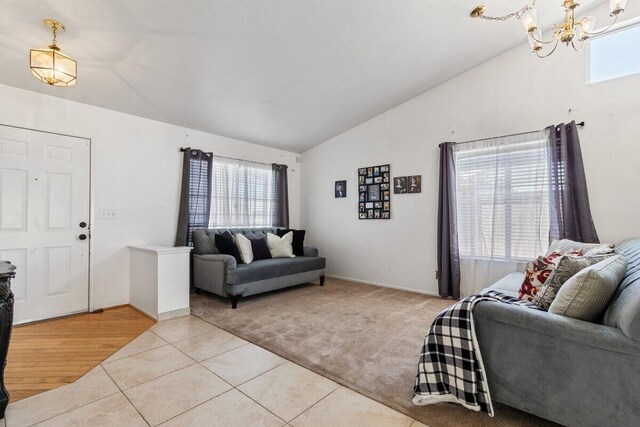 living room with light colored carpet, an inviting chandelier, light tile patterned floors, and lofted ceiling
