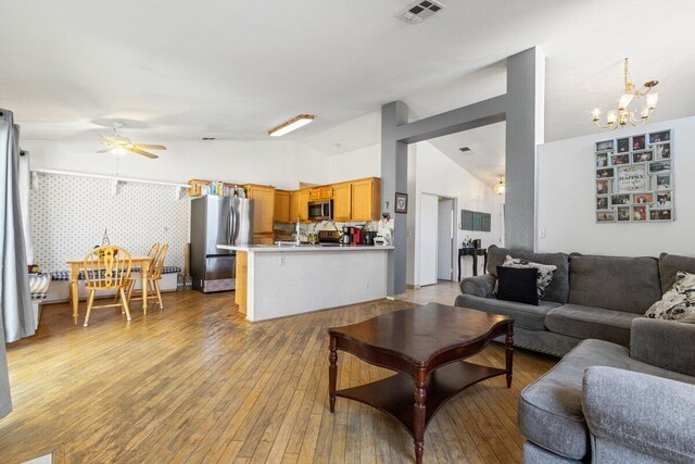 living room with visible vents, ceiling fan with notable chandelier, light wood-type flooring, and lofted ceiling