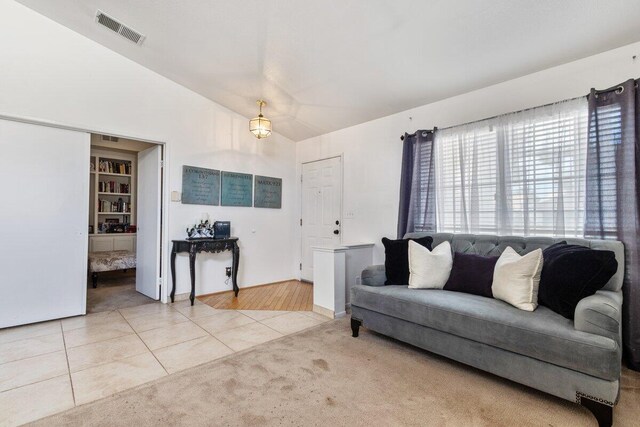 carpeted living area with visible vents, lofted ceiling, and tile patterned floors