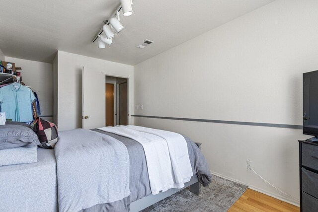 bedroom with visible vents, track lighting, and light wood-type flooring