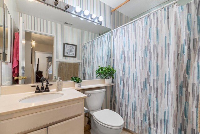 full bath featuring visible vents, vanity, curtained shower, toilet, and wallpapered walls