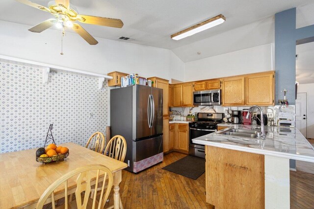 kitchen featuring dark wood-style flooring, appliances with stainless steel finishes, a sink, light countertops, and a peninsula