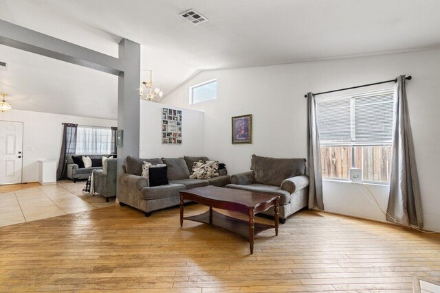 living area featuring visible vents, lofted ceiling, a notable chandelier, and light wood-type flooring