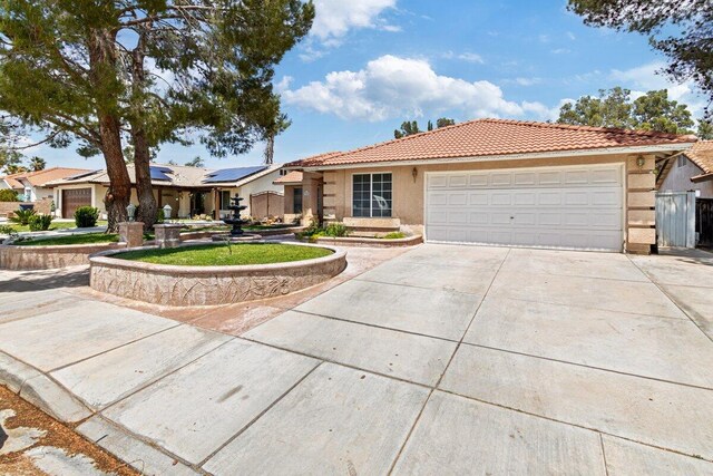 view of front of home featuring a tile roof, a garage, roof mounted solar panels, concrete driveway, and stucco siding