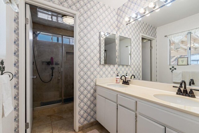 full bathroom featuring double vanity, wallpapered walls, a sink, and a stall shower