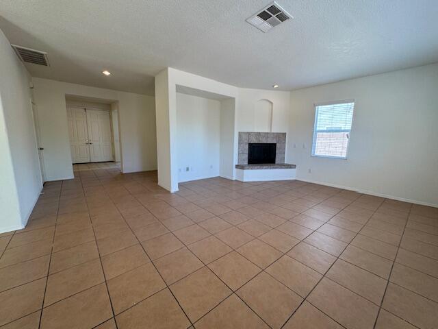 44316 Acacia St, Lancaster, CA 93535 - unfurnished living room featuring light tile patterned floors, a tiled fireplace, a textured ceiling, and recessed lighting