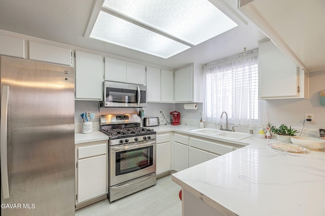 43840 Bobby Jones Dr Apt 22, Lancaster, CA 93536 - kitchen with stainless steel appliances, white cabinets, light wood-type flooring, and light stone countertops
