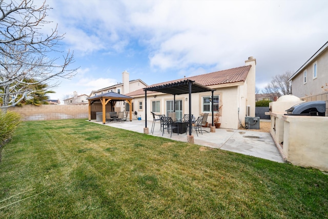 back of property with a gazebo, an outdoor kitchen, a yard, and a patio