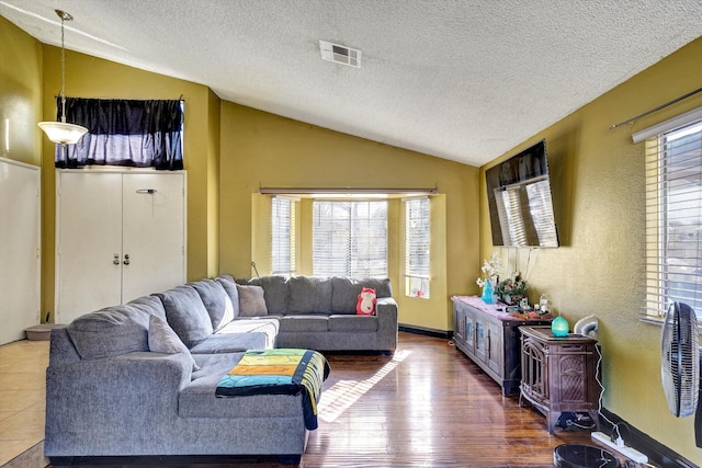 living room featuring hardwood / wood-style flooring, a textured ceiling, and vaulted ceiling