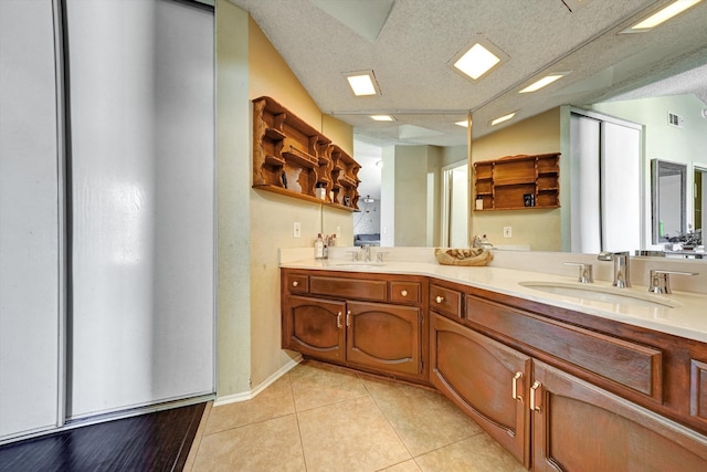 bathroom with tile patterned flooring, a textured ceiling, vaulted ceiling, and vanity