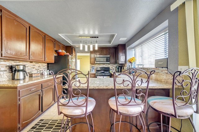 kitchen featuring gas range, kitchen peninsula, light tile patterned floors, and tasteful backsplash