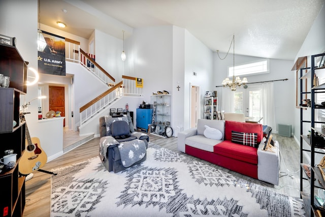 living room with stairway, high vaulted ceiling, wood finished floors, and a chandelier